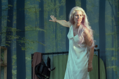 Titania (played by Jenny Rainsford) gestures emphatically in distress. This is a production of “A Midsummer Night’s Dream” performed at Regent’s Park Open Air Theatre (London) in 2026. Photography by Marc Brenner.